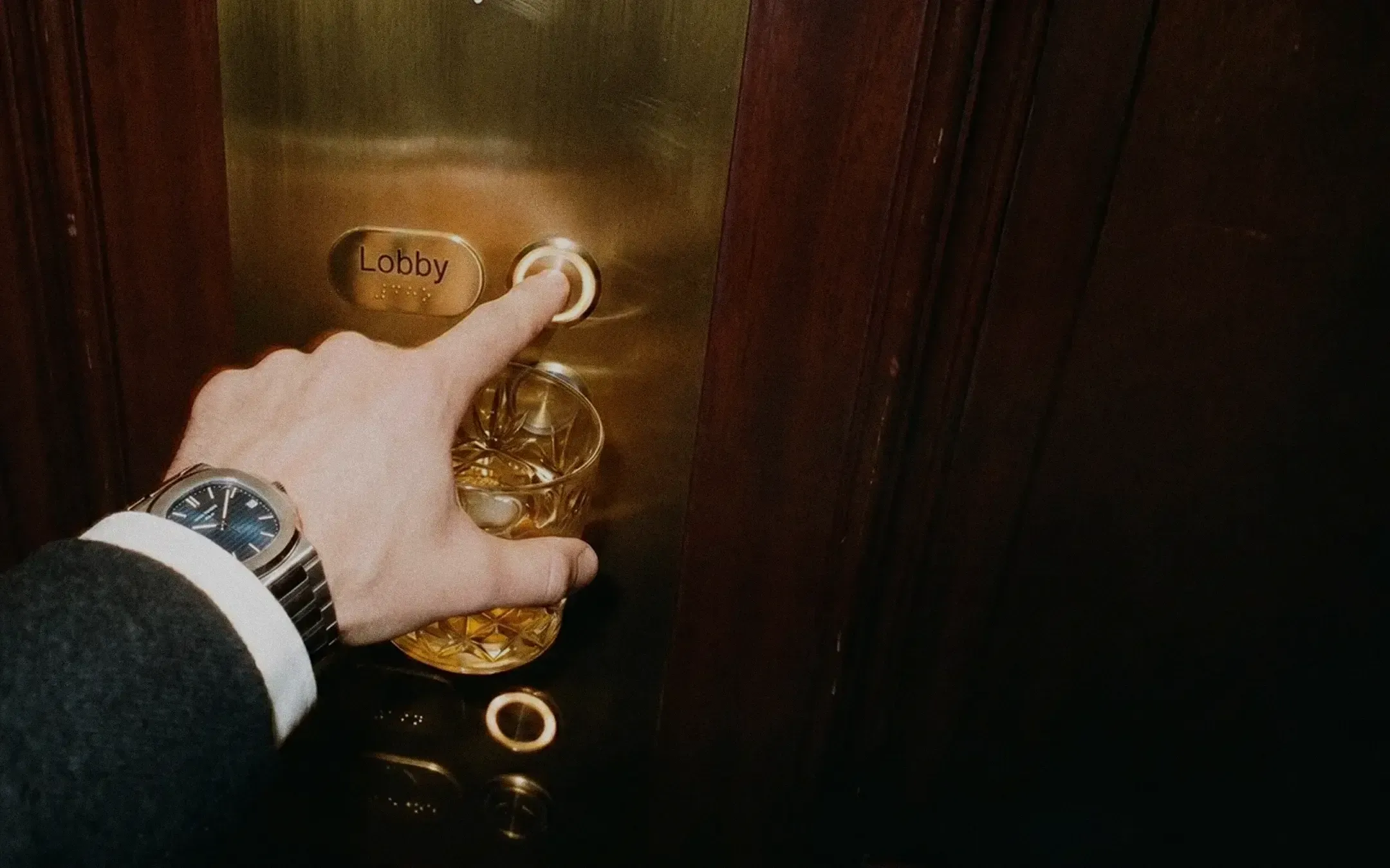 A hand holding a whiskey glass at a bar