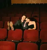 Two people lounging in red cinema seats